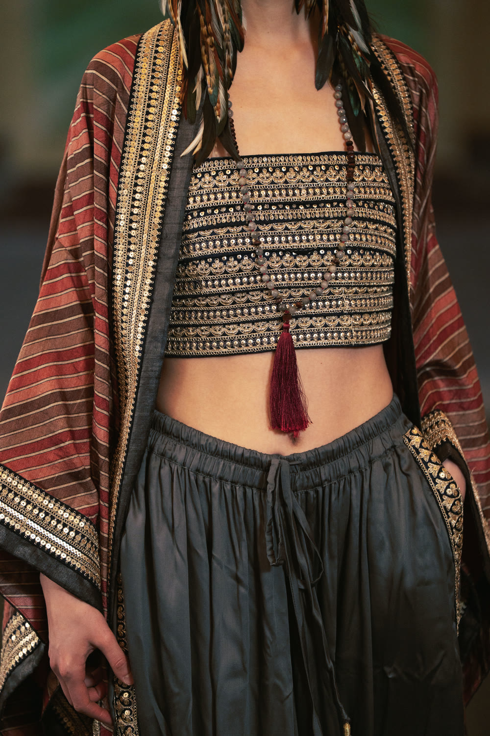 Close view of the striped kimono over the embroidered bralette and grey wide pant.