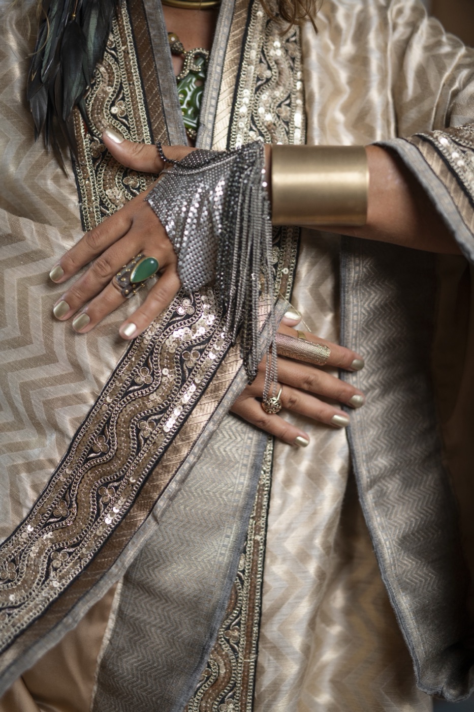 Hands with rings and a gold cuff on a sequinned brocade kimono.