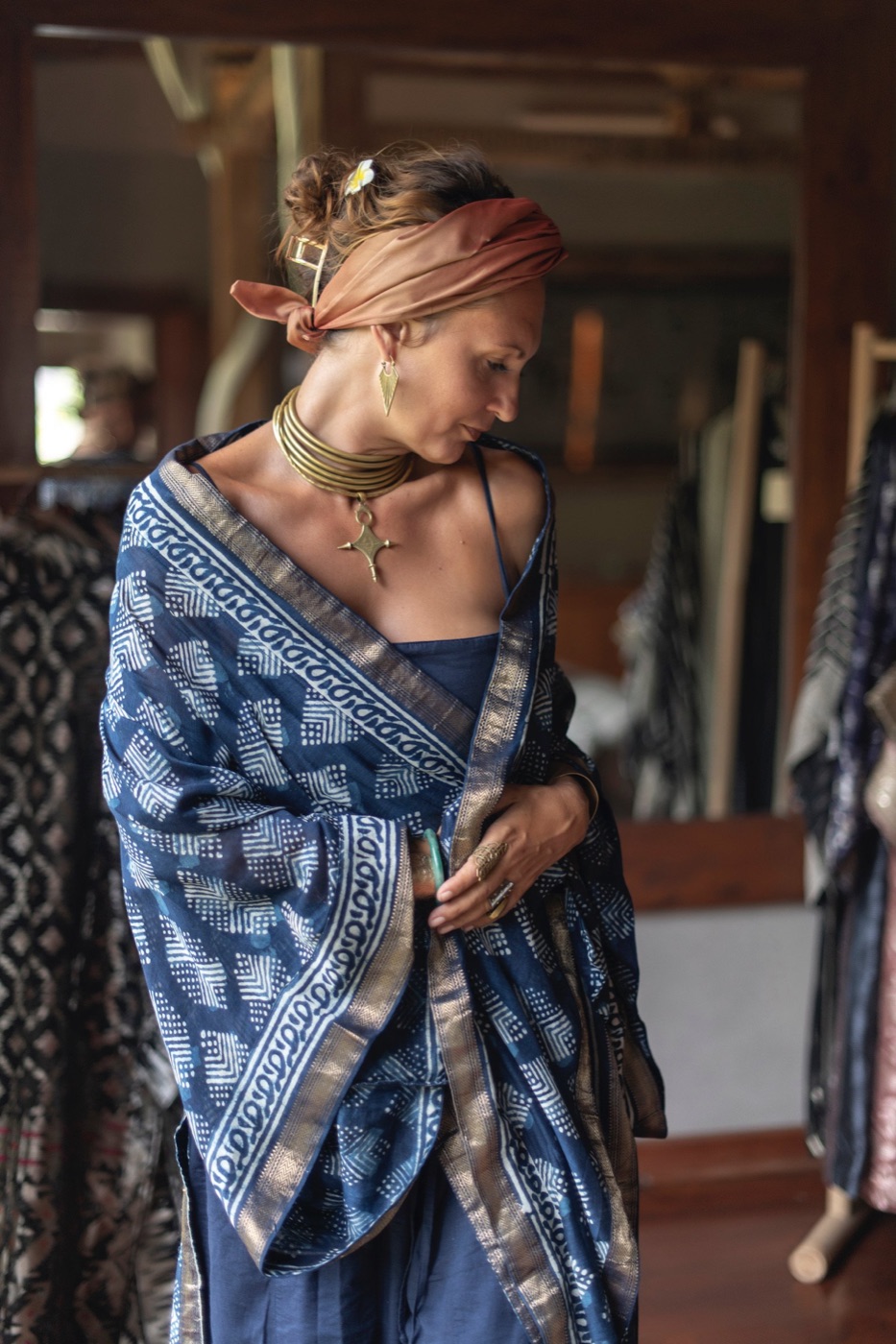 A woman in an orange headwrap looking down at an indigo block printed shawl.