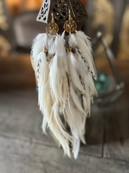 Cream feather earrings hanging from a lantern.